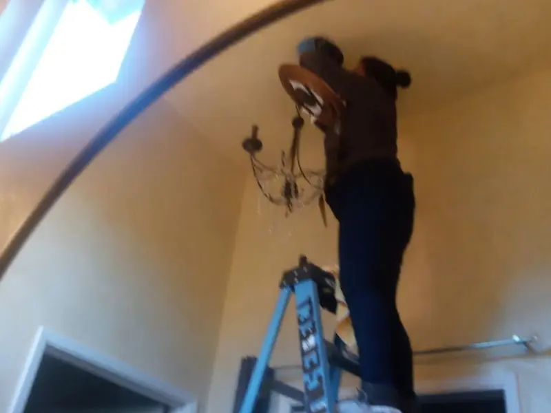 Electrician installing a chandelier in a Alma residence